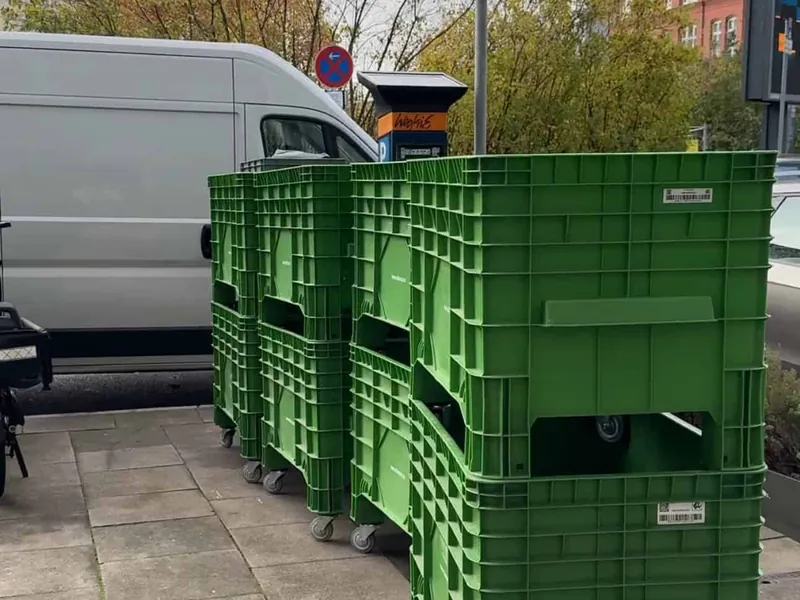 Grüne Mehrweg-Umzugsboxen vor einem Hamburger Wohnhaus